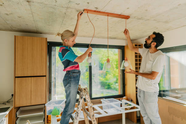 Photo of a young couple fixing lighting equipment in their new home Lighting and Electrical Upgrades